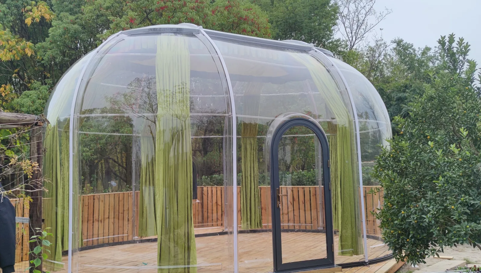 Transparent Celenest dome on a timber deck in a planted garden
