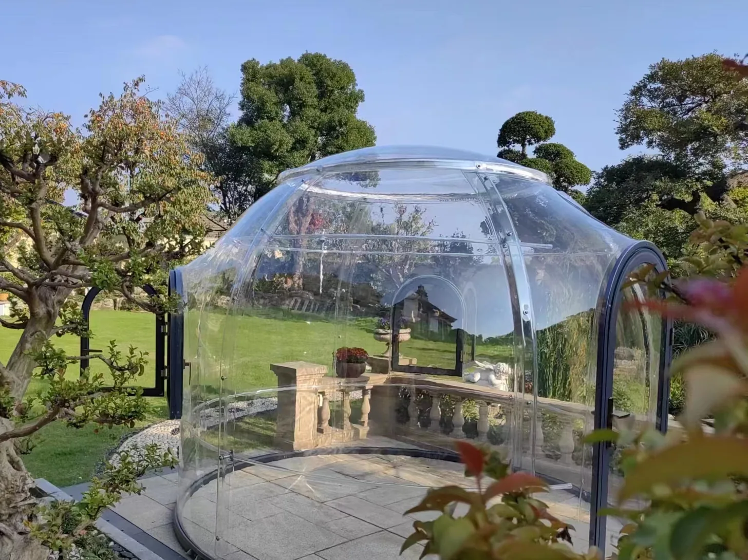 Clear polycarbonate garden pod installed on stone paving in a private landscaped garden