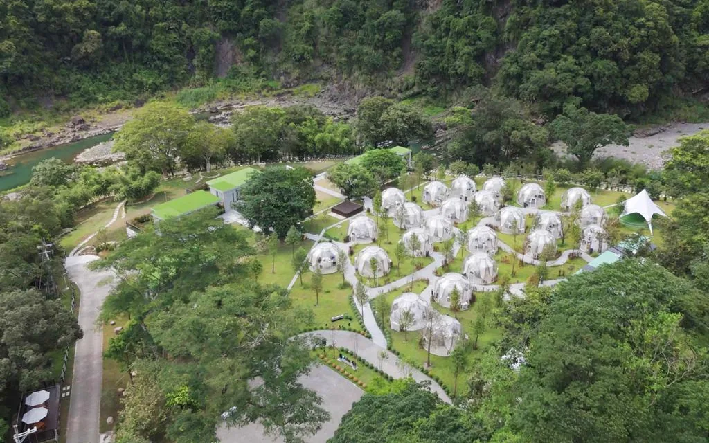Multiple transparent domes arranged across a landscaped hospitality site