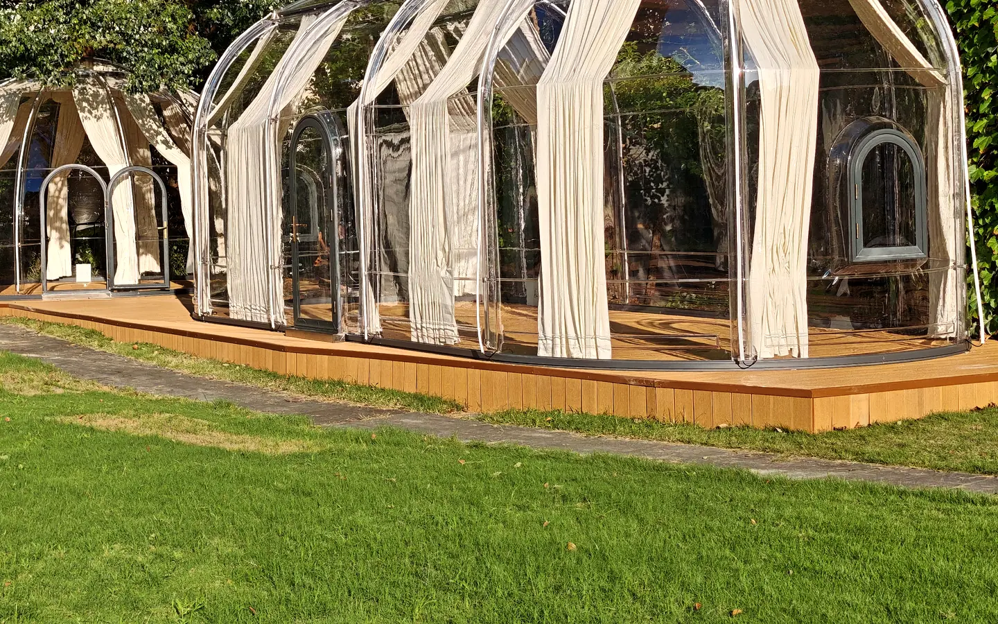 Extended oval Celenest dome with curtains on a timber deck