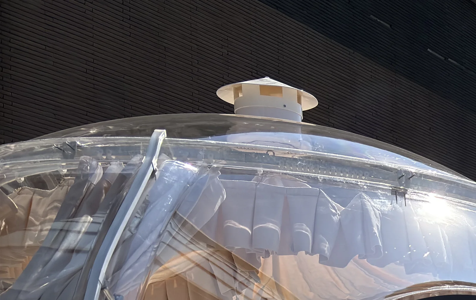 Curved solid polycarbonate shell with its crown vent and panel seam in direct sunlight